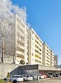 Multi-story apartment building with a parking lot in front, surrounded by trees covered in snow