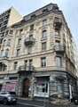 Multi-story building with ornate architectural details, including arched windows, decorative balconies, and intricate stone carvings. The building has a mix of modern and historic elements, with a Point Copy store on the ground floor.