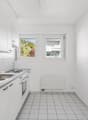 kitchen area, sink, oven, gas stove, windows, tiled floor, white cabinets