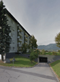 2-story apartment building with garage, surrounded by trees, on a hill