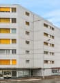 modern white high-rise building, yellow shutters, commercial spaces on the ground floor, street light