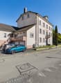 2-story house, tan and pink exterior, brown roof, large windows, 2 cars parked in garage, driveway