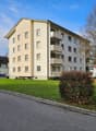 4 story building, beige exterior, balconies, windows, green lawn, street