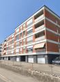 5 story apartment building, brick and white wall, balconies, car parked in front
