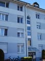 apartment building, white exterior, brown roof, multiple windows, glass door, garage