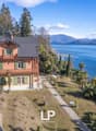2 story house, red brick, green windows, solar panels, located on a hill, with a sea view