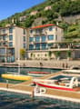 Building with multiple floors and terraces overlooking water, boats docked in front