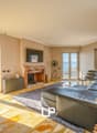 Spacious living room with large windows, balcony, fireplace, leather sofa, and modern decor