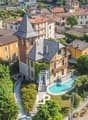 Aerial view of a building complex with houses of different colors, one house with a tower, a swimming pool in the garden