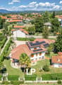 Multiple houses, solar panels on roofs, driveway, garden, greenery, trees, distant mountains, aerial view