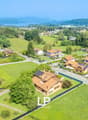 Detached house, red roofs, green landscape, visible solar panels, large green fields, mountain view in the distance, swimming pool on the side