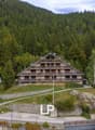 Large apartment building, nestled in a mountainous setting, surrounded by trees, with a scenic mountain backdrop