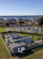 Modern building, solar panels on the roof, landscaped surroundings, parking lot, lush green fields