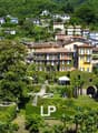 Cluster of houses in a hillside community, multiple pools, lush greenery, trees, distant mountain range