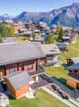 Group of detached chalets, wooden architecture, mountain view, surrounding greenery