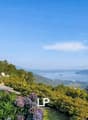 astonishing views of the mountains and the sea, beautiful landscaping, two white chairs, and potted plants