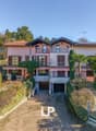 two-story house, pink exterior, brown roof, balconies, garage, raised ground floor