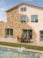 Modern house with stone facade, large windows, swimming pool, outdoor dining area, spacious lawn