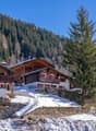 wooden chalet, red shutters, balcony, snow-covered ground, mountain view