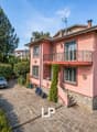 2 story house, pink exterior, brick ground floor, balcony, parking place, garden, trees