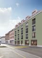 Urban apartment building, green exterior, balconies, commercial ground floor