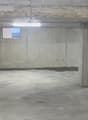 This image shows a large, empty concrete garage or storage space. The walls and floor are made of plain concrete, and there are a few small windows visible. The space appears to be unfinished and utilitarian in nature.