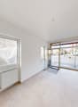 Large room, white walls, tile floor, glass window, radiator, two doors, leading to a parking area