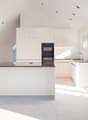 modern kitchen, island, white cabinets, black countertops, built-in oven and microwave, sink, skylights