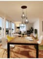 large windows, glass door leading to terrace, wooden dining table, modern chairs, large hanging lamps, framed picture on wall