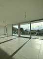 Spacious open-plan living area with large windows and sliding glass doors leading to a balcony or terrace, providing a scenic view of the surrounding mountains and landscape. The room features a minimalist design with light-colored tile flooring and white