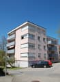 pink building, multiple balconies, two cars parked in front