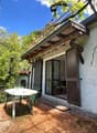 small single-family house, white wall, wooden balcony, brown shutters, open door, small garden table