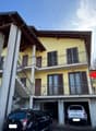 2-story yellow building with wooden roof, balconies, and a garage on the ground floor.