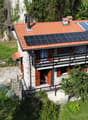 2 story house, stone walls, red roof, raised ground floor, solar panels, terrace