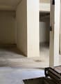 Empty room with concrete floor, white walls, two doors, and a wooden ramp.