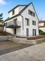 2 story white house, black windows, balcony, driveway, trees