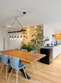 dining table, wooden chairs, kitchen island with cooking area, open shelves, modern pendant light, orange cupboards, wooden flooring