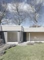 House exterior with two floors, large windows, well-manicured garden, concrete structure, trees in the background.