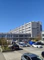 Large office building with multiple floors, surrounded by a parking lot with many cars parked.