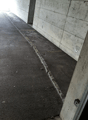An empty concrete garage with a grey parking area and concrete walls. There is an access point with a white electrical socket