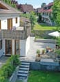 white house, brown roof, balcony, paved patio, garden, steps