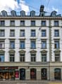 white facade, multiple windows, Starbucks Coffee shop on the ground floor, streetlights and wires above