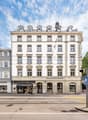 5 story white building with many windows, street level cafes