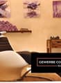 The image shows a relaxing spa or massage room with a comfortable reclining chair, wooden furniture, and decorative elements like framed artwork and vases with flowers. The room has a warm, calming atmosphere with a fireplace and what appears to be a balc