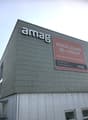 Office building, gray exterior, large sign reading 'amaq', another sign with contact information and services offered