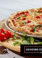 Whole pizza with tomatoes and basil on a plate with some cherry tomatoes around it.