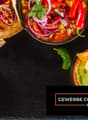 Mexican food such as tacos, salsa, chips, guacamole, soup, vegetables, garlic and chili peppers