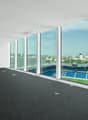 Large open office space with floor-to-ceiling windows overlooking a sports stadium and city skyline. The space has a black tile floor and white walls. There are several lighting fixtures installed in the ceiling.
