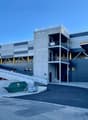 A large, modern commercial building with a gray and blue exterior. The building has multiple floors and a raised platform for loading and unloading. There is a dumpster visible in the foreground, indicating this is likely a storage or warehouse facility.