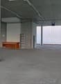 Empty concrete room, concrete flooring, large glass windows, small wooden desk.